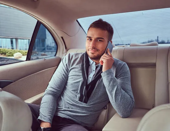 Uomo in auto di rappresentanza che parla al telefono durante un trasferimento business.